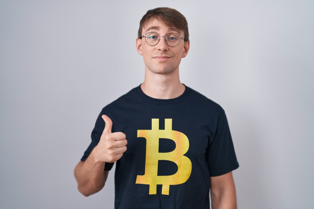 Guy in a Bitcoin t-shirt smiling and giving a thumbs up