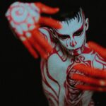 Artistic image of a man covered in red paint, representing the sexy-spooky vibe of Colombian folklore monsters for CamboysHub’s Halloween flirting guide.