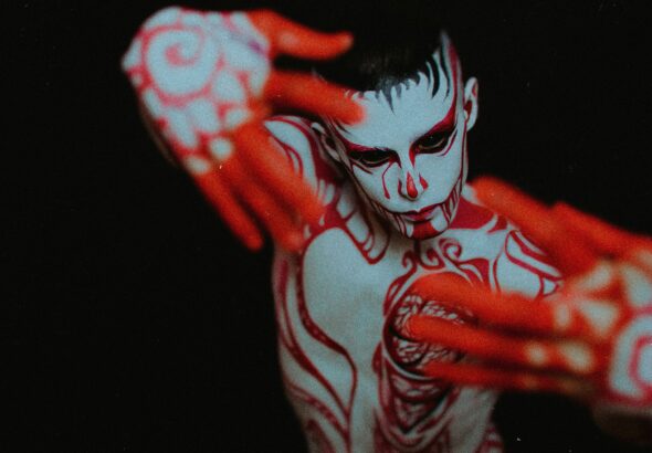 Artistic image of a man covered in red paint, representing the sexy-spooky vibe of Colombian folklore monsters for CamboysHub’s Halloween flirting guide.
