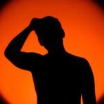 Silhuett av en person foran en oransje solnedgang