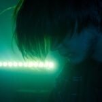 Man illuminated by green neon light