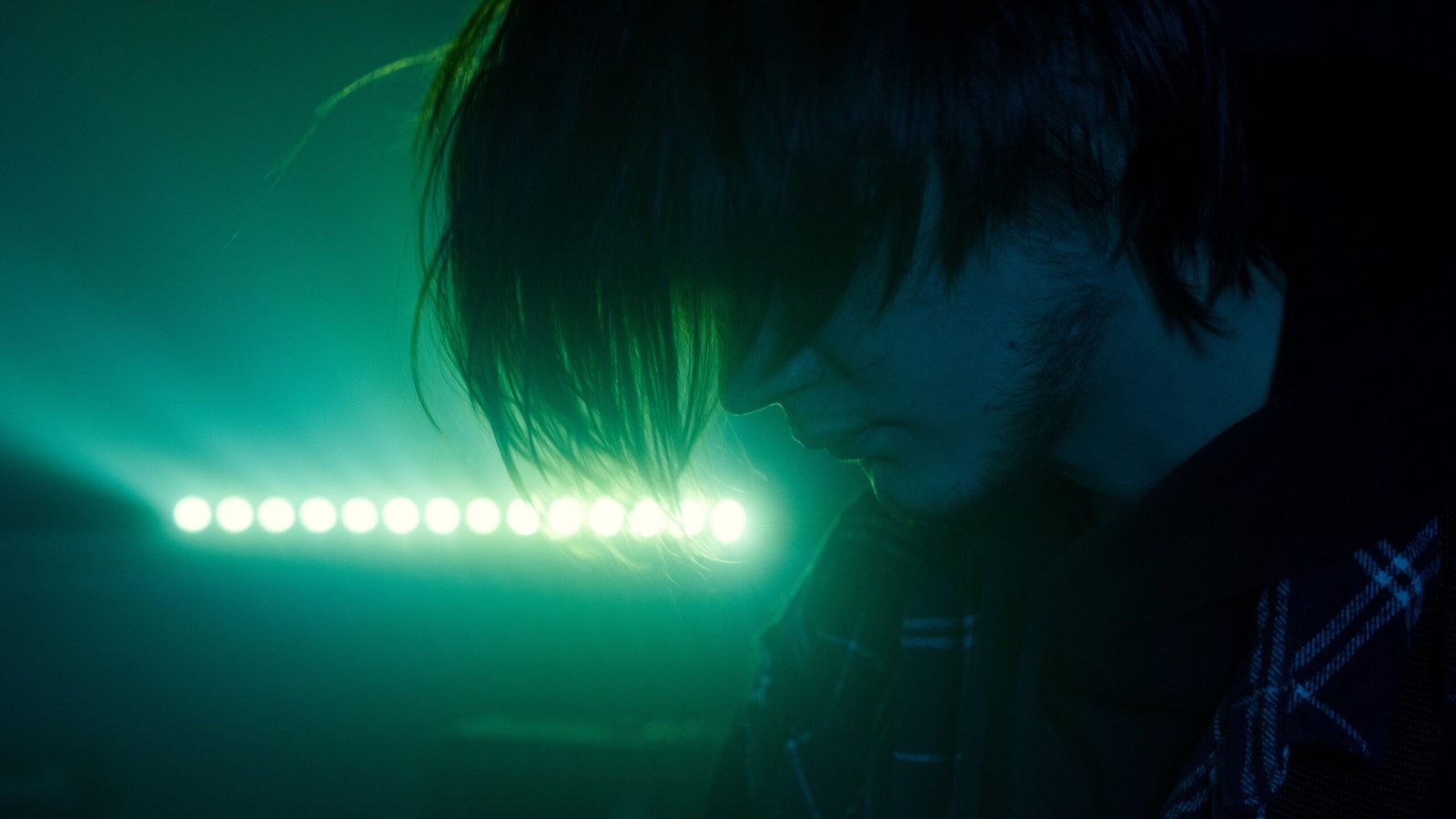 Man illuminated by green neon light